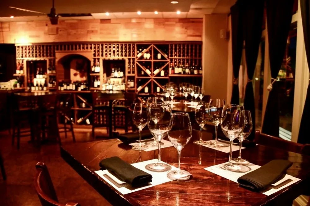 Tables set for a wine tasting, with glasses and napkins in front of the wine racks