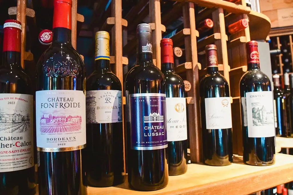 Bordeaux reds on the wine racks, including Château Fonfroide and Château de Lussac
